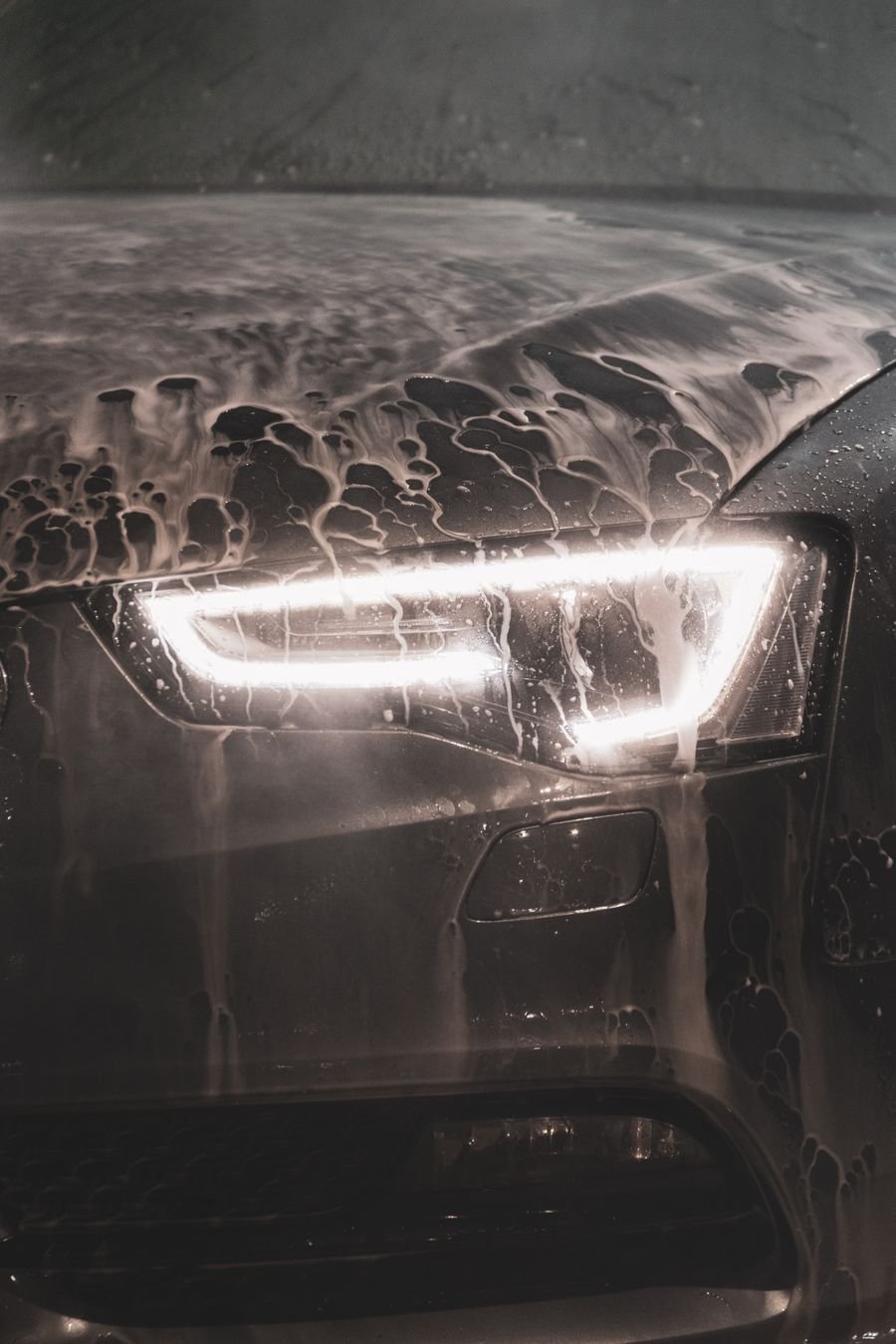 Headlight and hood covered in foam during a hand wash