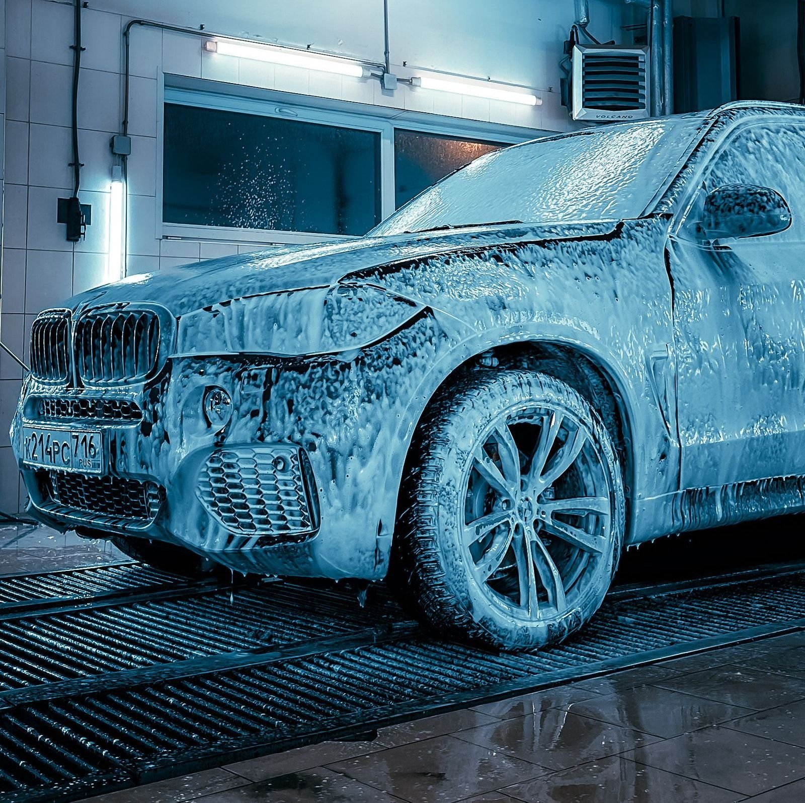 Car covered in foam inside the wash bay at night
